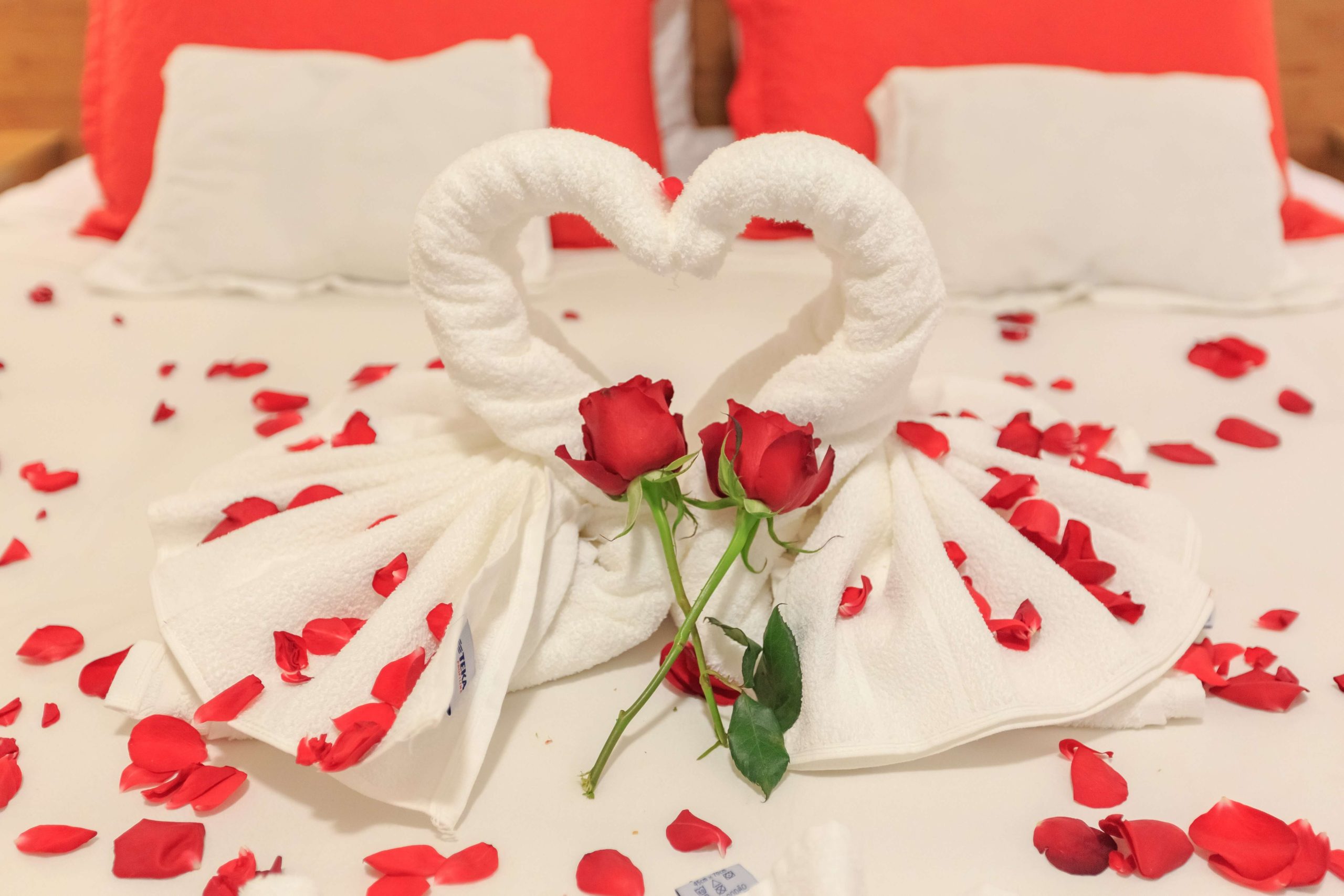 Lit d'un hôtel romantique en Provence-Alpes-Côte d'Azur avec des roses et des serviettes formant un cœur